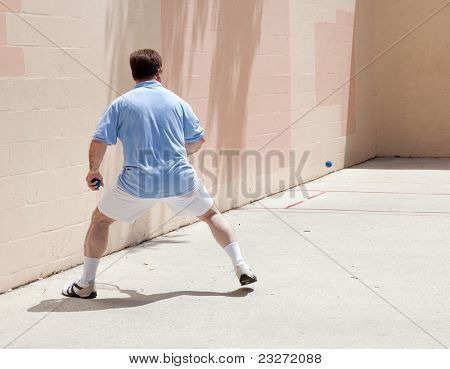Poloviny dospělého muže hrát squash na veřejném hřišti.