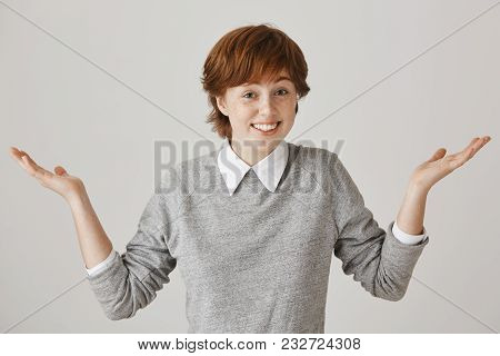 I Have No Clue. Portrait Of Carefree Cute Redhead Female Model With Freckles Shrugging And Standing 
