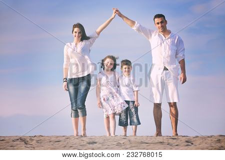 happy young family have fun on beachand showing home sign with conncected hands while protecting childrens