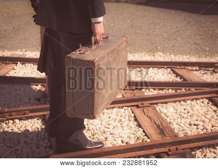 Young Couple With Vintage Suitcase Walking On The Trainlines Ready For A Journey.