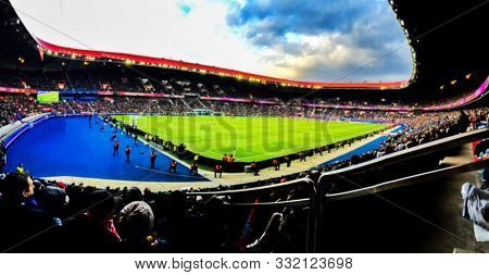 Blurred Background Of Football Players Playing And Soccer Fans In Match Day On Beautiful Green Field