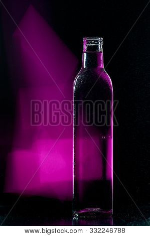 Empty Glass Bottle On A Black Background With A Long Exposure Backlit Background