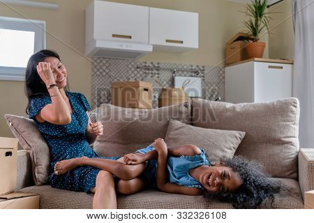 Mom And Daughter Multiraces Move To A New Apartment. Have Fun Jumping And Playing On Sofa.