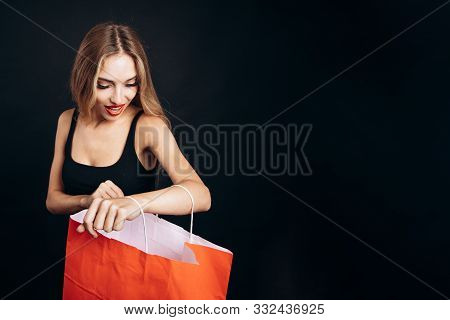Pretty Young Girl Admiring Her Trendy Purchase In Paper Bag