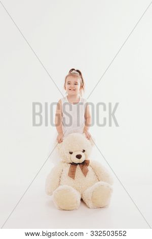 A Small Child With Toy Taddy Bear. Girl Playing On White Background. Concept Of Gift, Childhood