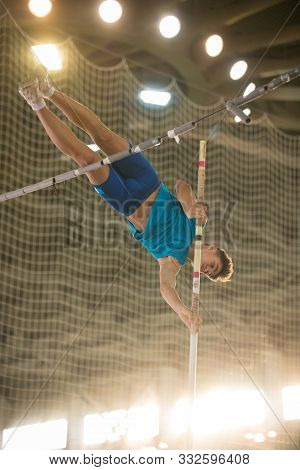 Pole Vaulting - Guy Is Jumping Over The Bar Holding On To A Pole