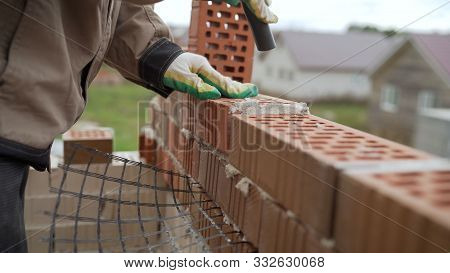 Worker Builds A Wall Of Red Silicate Brick.. Bricklayer Build Walls In Accordance With Construction 
