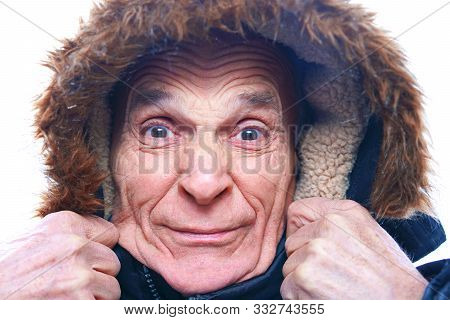 Old Senior Man In A Blue Warm Winter Jacket, Holding A Fur Hood With His Hands, His Face In Wrinkles