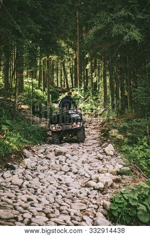 Man On All-terrain Vehicle Ride By Stone Trail In Forest