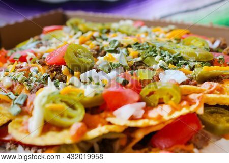 Take Out Box With Nachos Topped With Beef, Jalapenos, Tomatoes, Onions And Cheese,