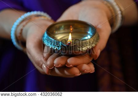 Woman Holding Lit Diya Lamp In Hands, Closeup. Diwali Celebration