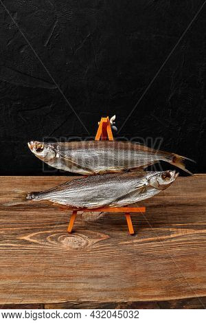 Two Air-dried Sabrefish On Serving Stand On Black Background