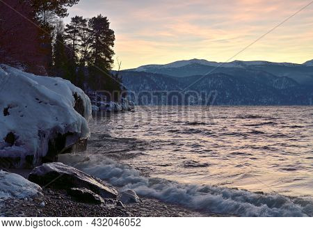 Teletskoye Lake Does Not Freeze In Winter. Waves Of Surf, Snow, Ice And Icicles, Rocks On The Shore,