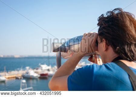 Man Looks Through Stationary Binoculars. Binoscope On Observation Deck Near Sea. Seaport In Odessa. 