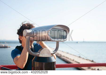 Man Looks Through Stationary Binoculars. Binoscope On Observation Deck Near Sea. Seaport In Odessa. 
