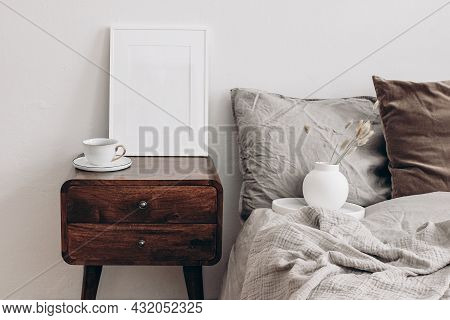 Vertical White Picture Frame Mockup. Retro Wooden Bedside Table. Modern White Ceramic Vase With Dry 