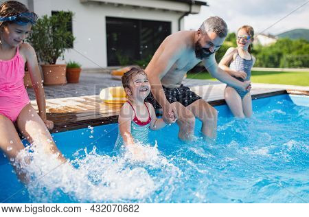 Father With Three Daughters Outdoors In The Backyard, Playing In Wimming Pool.