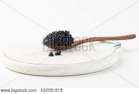 Fresh Grainy Black Paddlefish Caviar In Brown Wooden Spoon On White Background, Close Up