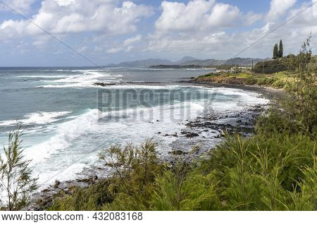 Ocean Waves Break On The Volcanic Rocks Strewn Along The Shore In Kapaa, Kauai, Hawaii.