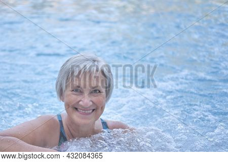 Close-up Portrait Of Smiling Senior Woman With Gray Hair Looking At Camera In Outdoor Thermal Pool W