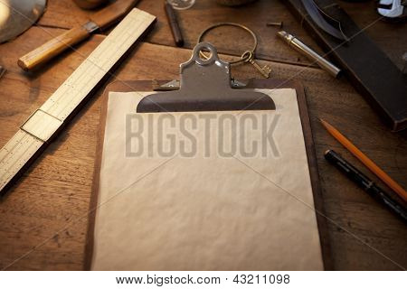 Clipboard and old parchment like blank paper under incandescent light, with vintage feeling.