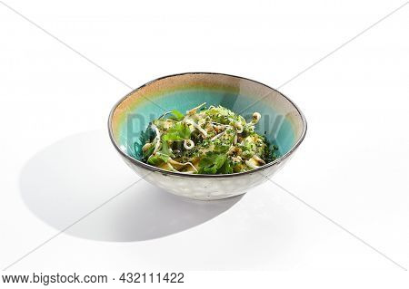 Chinese smashed cucumber with greens and sesame oil. Healthy vegetarian green salad with cracked cucumber and fresh green leaf. Healthy salad recipes concept. Salad bowl isolated on white background