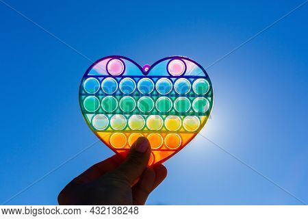 Colorful Antistress Sensory Toy On The Background Of Blue Sky. Pop It Kids Game In Hand. Outdoor Gam