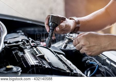 Close Up Spark Plug Coil In Hand A Man And Use Block Wrench Remove A Bolt In Service In Garage And E