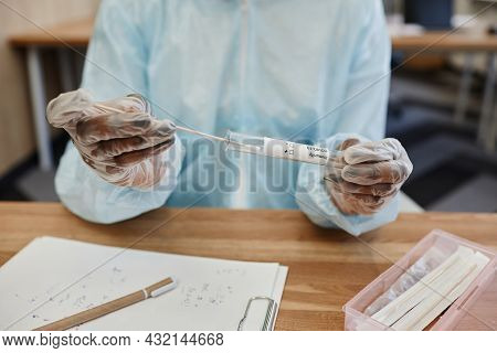 Hands Of Physician In Ppe Suit Putting Swab With Nose Mucus Of Patient In Test Tube To Send To Labor