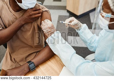 Doctor In Ppe Suit Giving Second Shot Of Vaccine Against Coronavirus To Male Patient In Clinic
