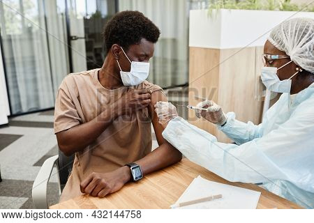 Young African American Man Sitting At Doctors Office And Getting Flu Shot In His Arm
