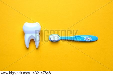 A Picture Of Fake Tooth With Tooth Brush On Yellow Board. Take Good Care Of Your Dental