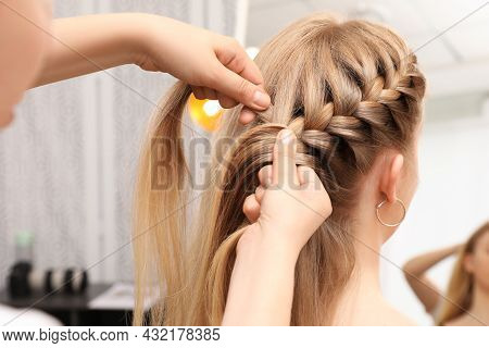 Professional Stylist Braiding Client's Hair In Salon