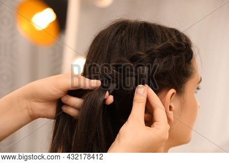 Professional Stylist Braiding Client's Hair On Blurred Background, Closeup