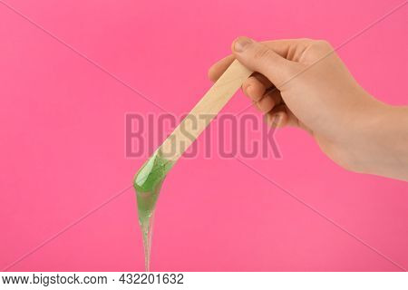 Woman Holding Spatula With Hot Depilatory Wax On Pink Background, Closeup