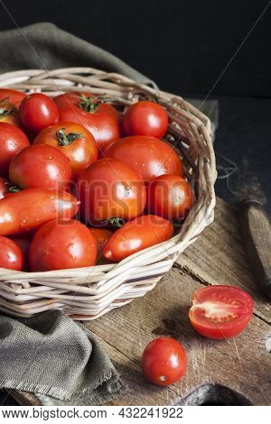 Fresh Red Tomatoes In Whicker Basket On Black Background.