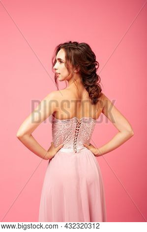 Rear View Of Back Of Elegant Woman In Delicate Elegant Pink Dress With Open Back, Isolated On Pink B