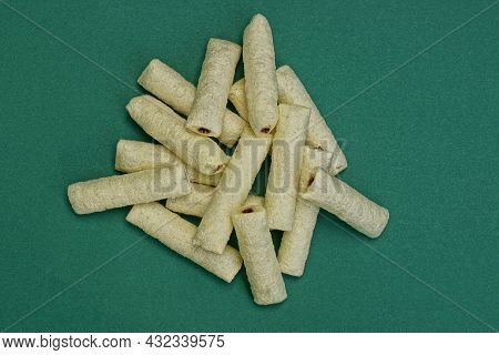 Food From White Long Corn Sticks With Chocolate Filling In A Heap Lie On A Green Table