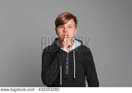 Dont Tell Anyone. Serious Young Boy Standing On Gray Studio Background, Looking At Camera And Doing 