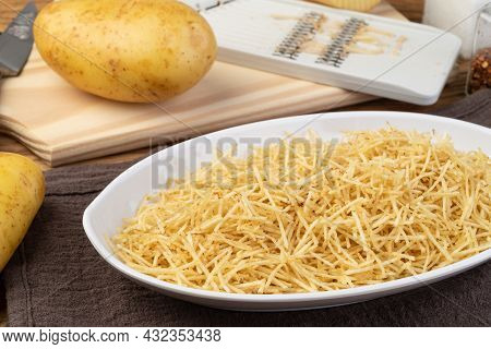 Potato Straw Or Shoestring Potato In A White Plate With Raw Potatoes.