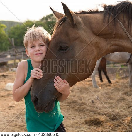 The Child Hugs The Horse With Tenderness. Love And Friendship With Your Pet. A Girl Or Boy Hugged Th
