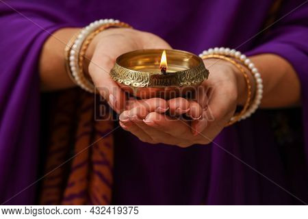 Woman Holding Lit Diya Lamp In Hands, Closeup. Diwali Celebration