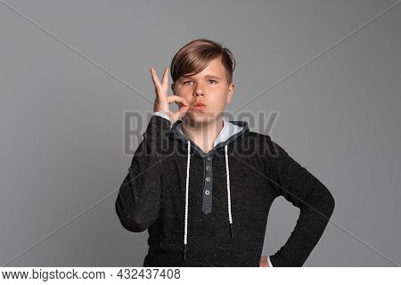 Serious Young Boy Showing Zip Gesture As If Shutting Mouth On Key, Standing Over Grey Background. Yo