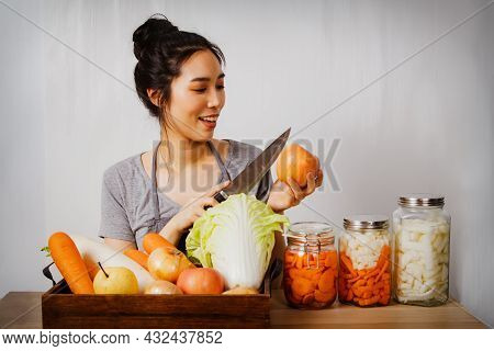 Asian Woman Preparing To Cut Fresh Apples And Raw Materials, White Cabbage, Carrots, Radishes, Fresh