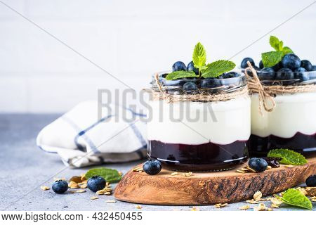 Parfait With Blueberry, Granola And Jam In Two Glass Jars.