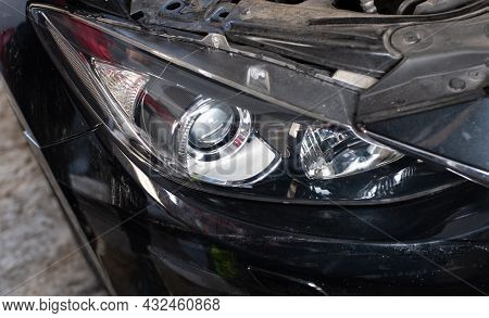 Close-up Front Headlight With Xenon Light Of Black Modern Car On Grey Background