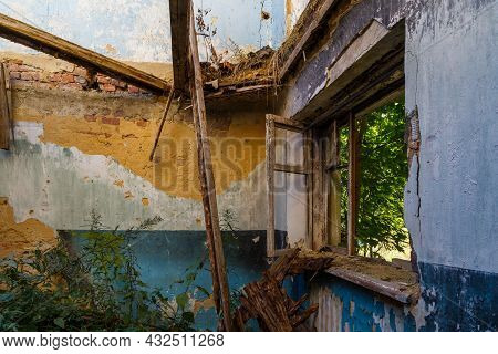 Broken Wooden Window And Room With Tall Grass, View Inside Of An Abandoned Half-destroyed Dormitory 