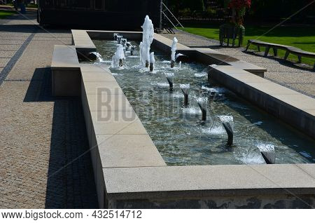 Swimming Pool With Fountains In The Shape Of An Opposite Cross On The Promenade In The Park On The S