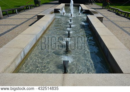 Swimming Pool With Fountains In The Shape Of An Opposite Cross On The Promenade In The Park On The S