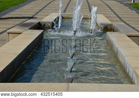 Swimming Pool With Fountains In The Shape Of An Opposite Cross On The Promenade In The Park On The S